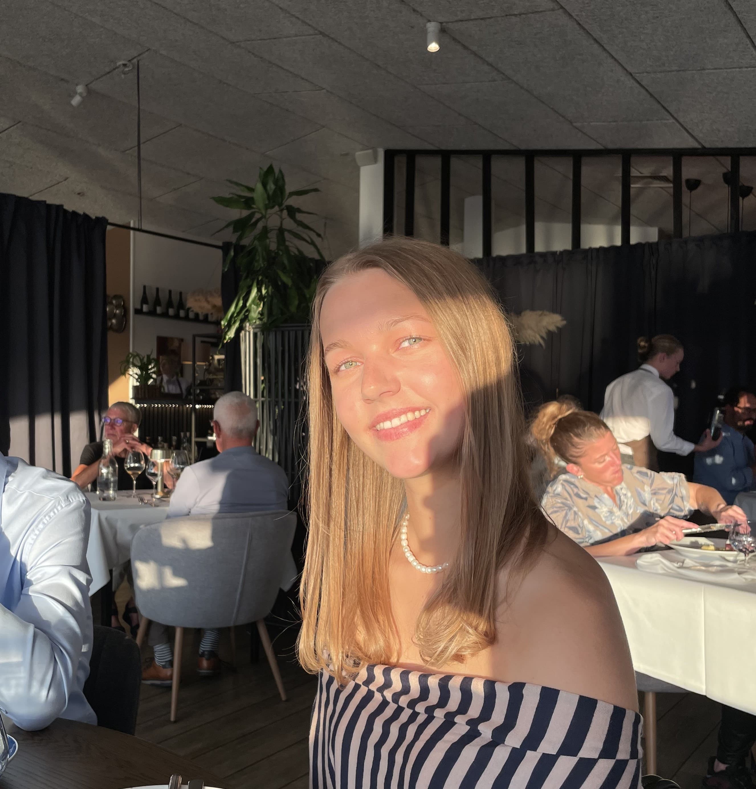 Fie sidder ved et bord i varmt aftensollys